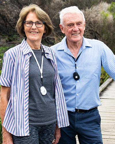 Happy senior couple wearing LiveLife personal emergency alarms