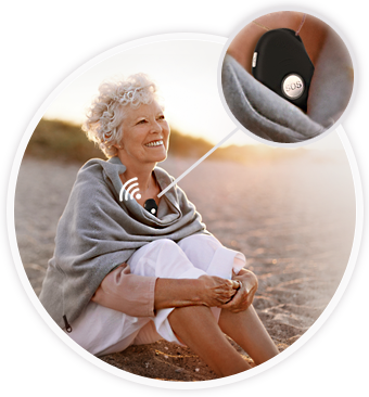 An elderly lady sitting in an Australian beach wearing 4gx live life alarm whose location can be found by sending SMS command to the alarms phone number