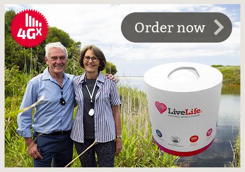 Australian couple walking in the riverside, wearing LiveLife medical alarm, looking at the camera