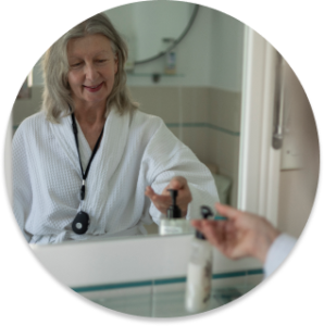 Happy senior lady in the bathroom setting, wearing a black LiveLife personal alarms