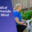 Two ladies smiling at each other, sitting in the garden. The lady on the right wears a medical alarm.