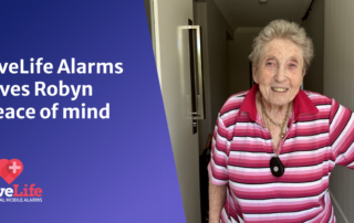 Elderly lady smiling at the camera, wearing a livelife alarm around her neck