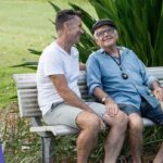 Carer supporting senior man who is wearing a Live Life personal alarm in the park